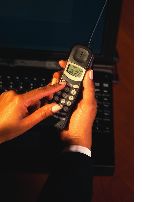 hands holding cell phone in front of computer